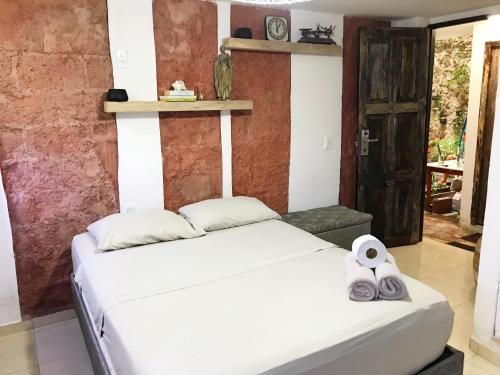 Un dormitorio con una cama blanca con toallas. en Casa Mamá Waldy New, en Cartagena de Indias