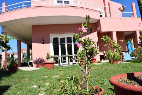 a pink house with a balcony and a yard at Private Villa AKOBARA, 2km from city center in Corfu Town