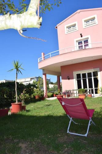 a red chair in front of a pink house at Private Villa AKOBARA, 2km from city center in Corfu Town