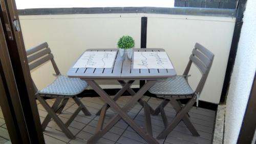 a table with two chairs and a potted plant on a balcony at Coquet appartement 5 places labélisé tout équipé in Saint-Lary-Soulan