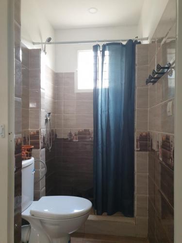 a bathroom with a toilet and a blue shower curtain at Jnane lkheir in Mansouria