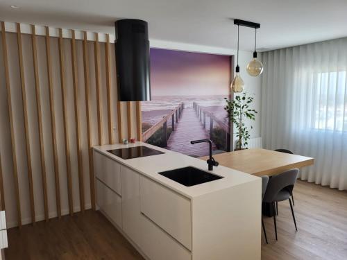 eine Küche mit einem Waschbecken und einem Tisch mit einem Gemälde eines Piers in der Unterkunft Apartamento Cinema para férias em Esposende in Esposende