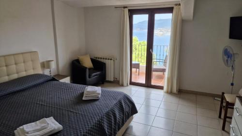 ein Schlafzimmer mit einem Bett und einem Stuhl sowie einem Balkon in der Unterkunft Hotel Sa Lumenera in Bosa