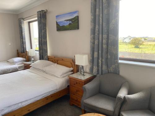 a bedroom with two beds and a chair and a window at Clonmore Lodge B&B in Quilty