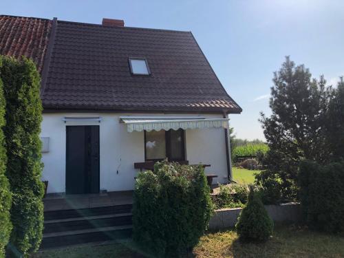 a white house with a black door and some bushes at Dom wypoczynkowy Zacisze in Filipów