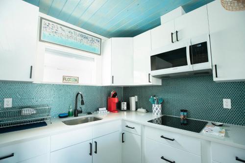 a kitchen with white cabinets and a blue tile wall at Casa Limonada Boutique Motel in Sarasota