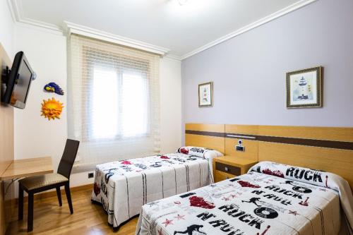 een kamer met 2 bedden, een tafel en een bureau bij piso vacacional en la playa de Rodeira in Cangas de Morrazo
