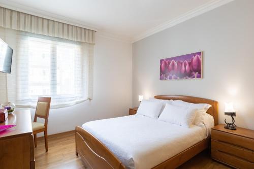een slaapkamer met een bed, een bureau en een raam bij piso vacacional en la playa de Rodeira in Cangas de Morrazo