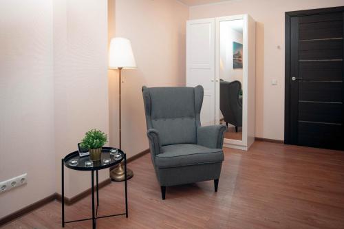 a room with a chair and a table and a lamp at Crown Apartment in Ukmergė