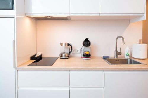 a kitchen with white cabinets and a sink at Crown Apartment in Ukmergė
