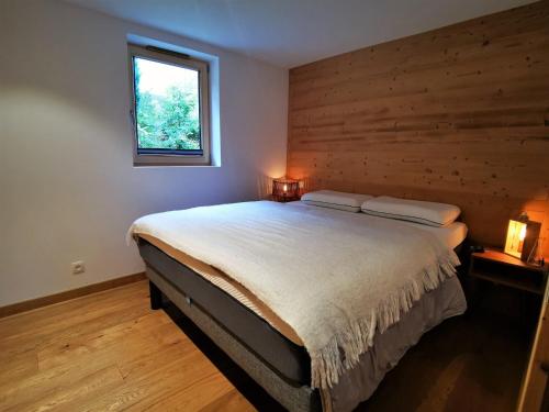 une chambre avec un grand lit avec un mur en bois dans l'établissement Appartement lumineux avec terrasse, proche pistes et commodités, Les Gets - FR-1-598-93, aux Gets