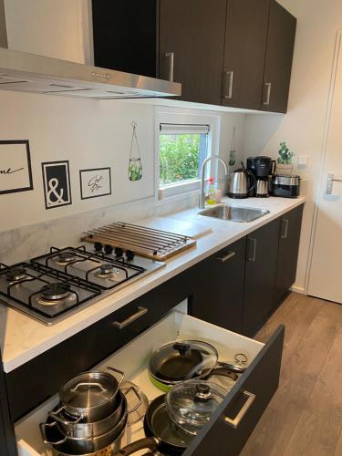 a kitchen with a stove with pots and pans on it at LUXUS Cube Ferienhaus Chalet am See mit Schwimmbad in Lathum NL in Lathum