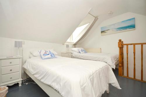 a bedroom with two beds and a window at Limpet Cottage in Brixham