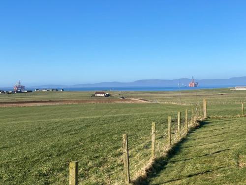 a fence in the middle of a green field at Loanside Lodge, Self-Catering, Holm, Orkney. in Saint Marys