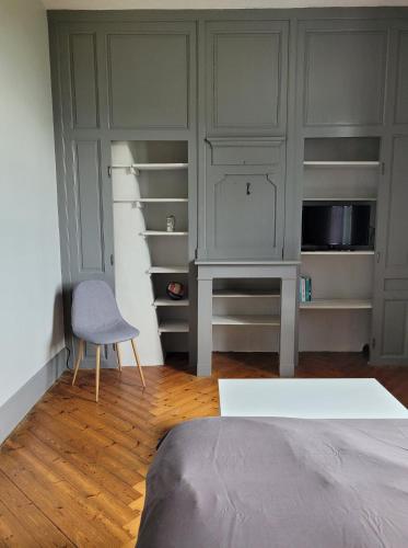 1 dormitorio con cama, silla y estanterías en Chambre chez l'habitant 1 en Biville-la-Baignarde