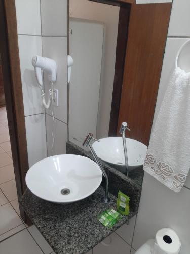 La salle de bains est pourvue d'un lavabo blanc et d'un miroir. dans l'établissement Pousada Sossego, à Penha