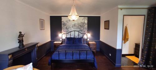 Un dormitorio con una cama azul y una lámpara de araña. en Ty Madelez, Chambres de charme, Gîtes, Crêperie et Spa en La Roche-Derrien