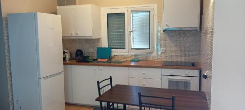 サラミスにあるBeachfront 3-bedroom apartmentのキッチン(白いキャビネット、テーブル、冷蔵庫付)