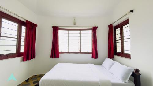 a bedroom with red windows and a white bed at Tranquiland in Kodaikānāl