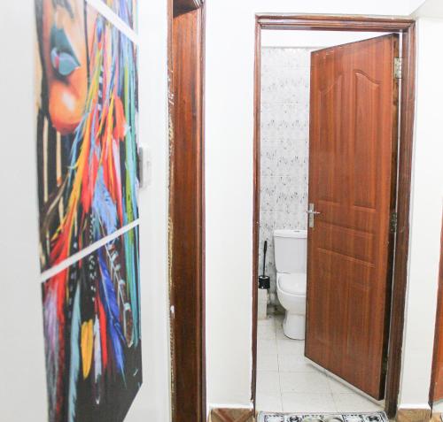 een badkamer met een schilderij aan de muur naast een toilet bij The Gem - Kiambu road 1 bedroom in Kiambu