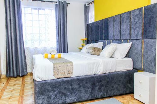 een slaapkamer met een groot bed met een blauw hoofdeinde bij The Gem - Kiambu road 1 bedroom in Kiambu
