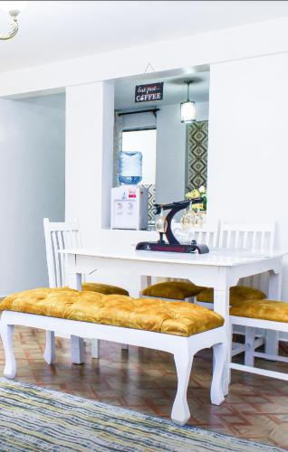 una mesa blanca con un banco con una máquina de coser en The Gem - Kiambu road 1 bedroom, en Kiambu