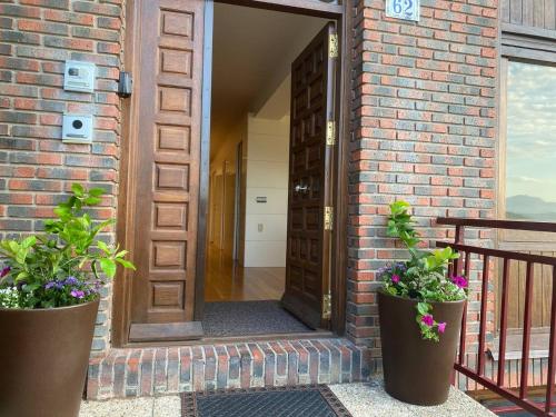 an open door of a brick building with two potted plants at Ondarreta Beach - Singular y exclusivo in Donostia-San Sebastián