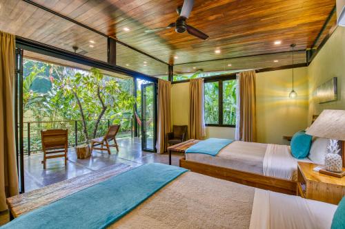 a bedroom with two beds and a large window at Villas Piña - Adults only in Puerto Viejo