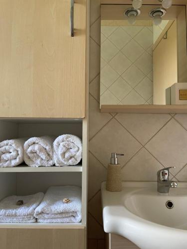 a bathroom with a sink and towels on a shelf at Sunny Villa in Kissamos
