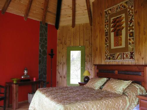 a bedroom with a bed with red walls and a window at Mapuyampay Lodge Gastronómico in Santa Cruz