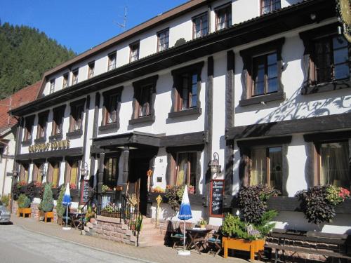 ein Gebäude mit Tischen und Sonnenschirmen davor in der Unterkunft Hotel Restaurant Albans Sonne in Bad Rippoldsau