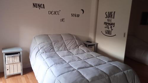 Una cama blanca en una habitación con palabras en la pared en Hermoso acogedor y hogareño apartamento duplex tipo loft suba la campiña, en Bogotá