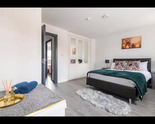 ein Schlafzimmer mit einem Bett mit einer grünen Decke in der Unterkunft Marston 5 Bedroom Home With Parking Near NEC & BHX in Marston Green