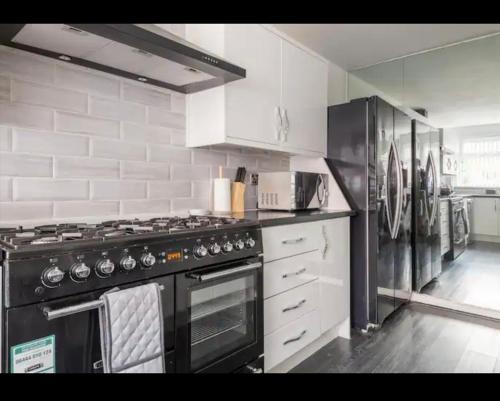 a kitchen with a black stove and a refrigerator at Marston 5 Bedroom Home With Parking Near HS2 & NEC & BHX in Marston Green