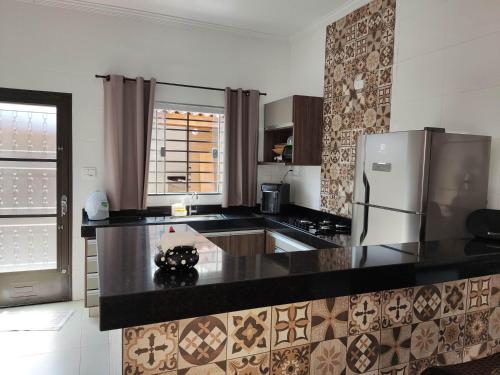 a kitchen with black counter tops and a refrigerator at Casa temporada AURORA in São João Batista do Glória