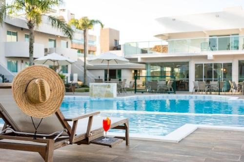 un sombrero de paja sentado en una silla junto a una piscina en Makkai Resort Bombinhas en Bombinhas