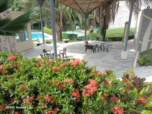 un patio con mesas, sillas y flores en Casa vacacional condominio bambú, en Carmen de Apicalá