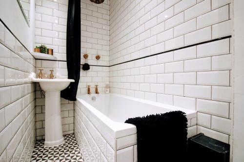 a bathroom with a white tub and a sink at Traditional Victorian 2 bed in cobbled street + mod cons - Full home in London