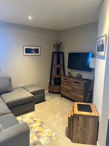 a living room with a couch and a flat screen tv at Loanside Lodge, Self-Catering, Holm, Orkney. in Saint Marys
