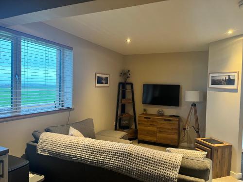 a living room with a couch and a tv at Loanside Lodge, Self-Catering, Holm, Orkney. in Saint Marys