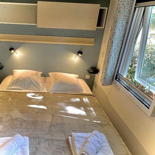 a bedroom with a bed with two pillows and a window at LES BASTIDES DE CHANTERAINE Bungalows, Lodges & Spa in Aiguines