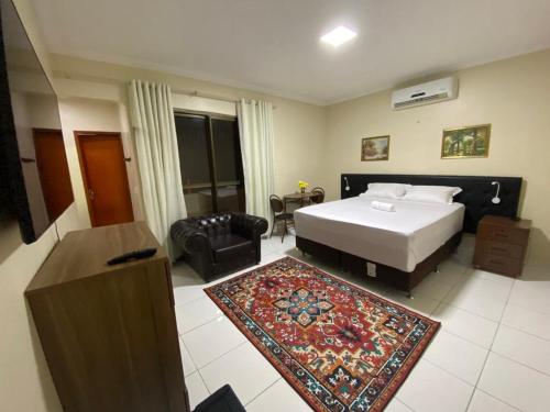 ein Schlafzimmer mit einem Bett, einem Stuhl und einem Teppich in der Unterkunft Bertolini Hotel in Quixadá