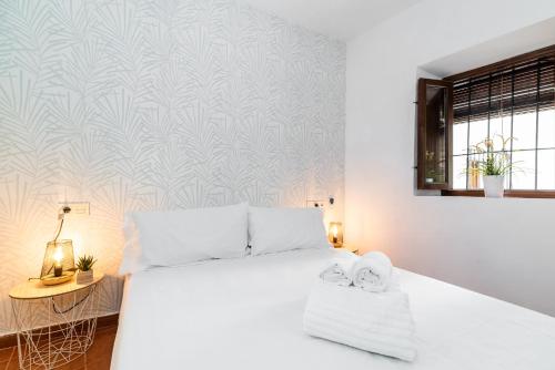 sypialnia z białym łóżkiem i ścianą w obiekcie Home4u Casa del Tesoro I w Grenadzie