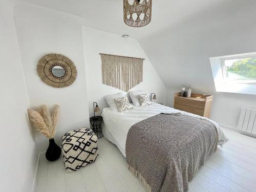 biała sypialnia z łóżkiem i lustrem w obiekcie Maison chaleureuse avec Jacuzzi w mieście Plouézec