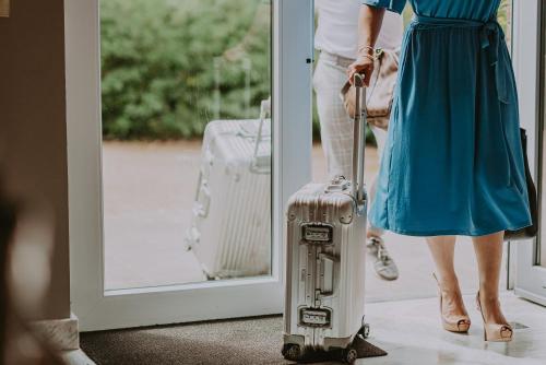 a woman in a blue dress pulling a suitcase at Villa Geva in Montignies-le-Tilleul