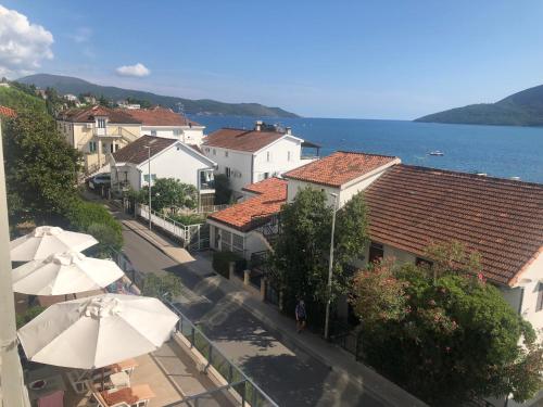 a town with a street with umbrellas and the ocean at Apartments Bane in Herceg-Novi