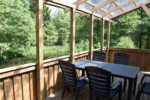 a table and chairs on a deck with a pergola at Daemningen at Gammel Rye in Ry