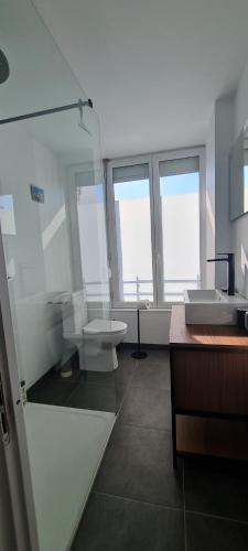 baño con lavabo, aseo y ventanas en Grande Maison dans le Bourg de Nevez + jardin en Névez