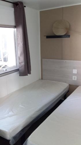 une petite chambre avec deux lits et une fenêtre dans l'établissement Mobil home 4-6 places St brėvin les pins 44, à Saint-Brévin-les-Pins