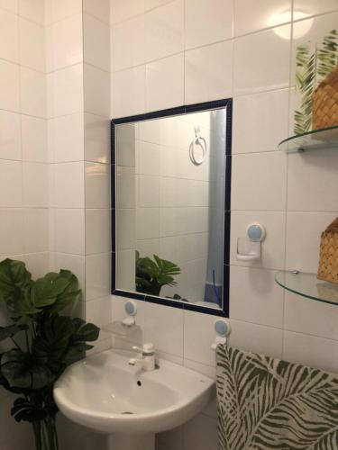 Baño blanco con lavabo y espejo en Calma La Barrosa Apartamento, en Chiclana de la Frontera